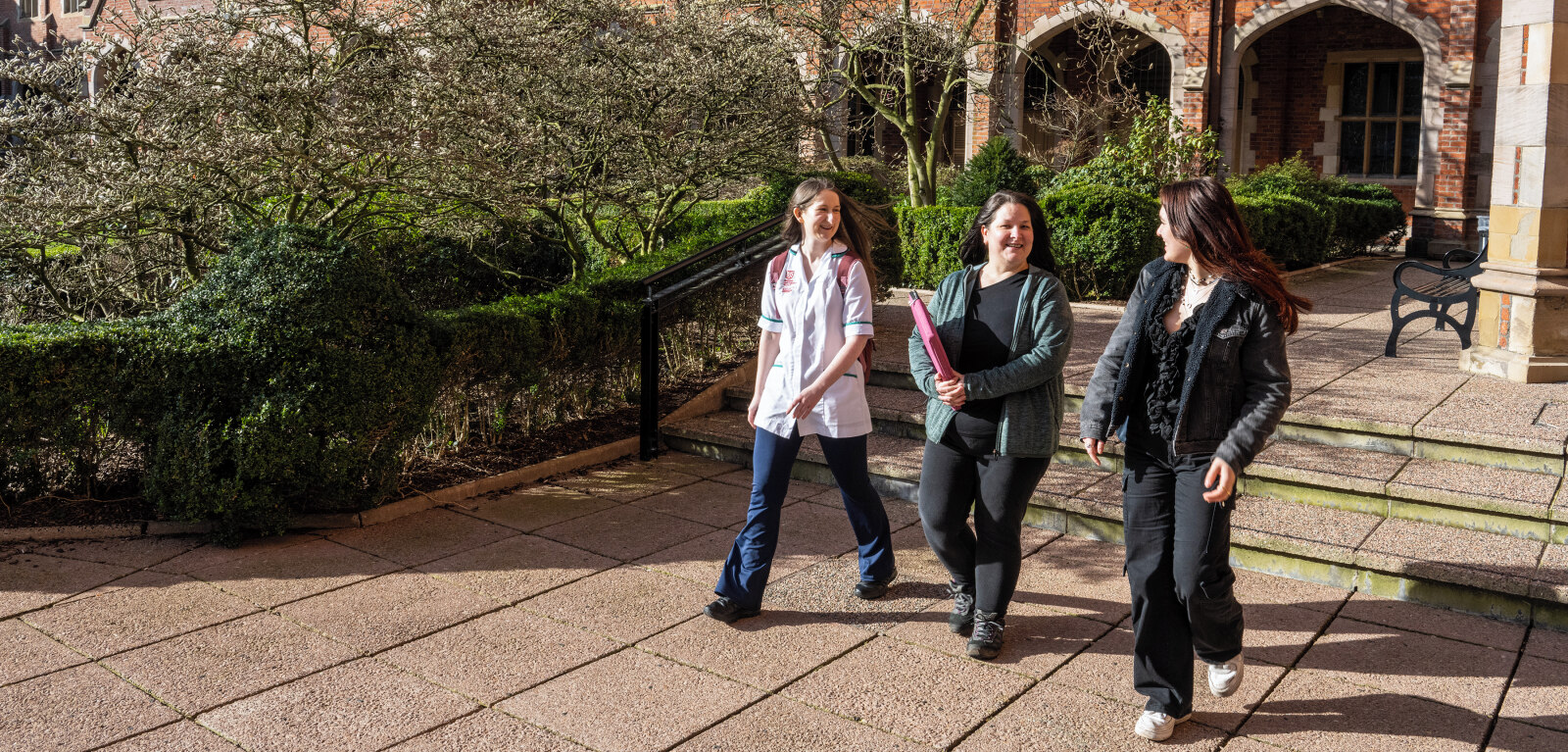 Three mature students walk through the Quad