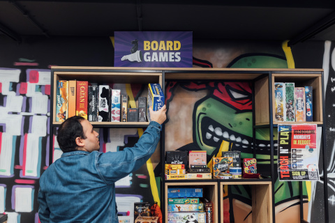 Student Miguel reaching for board game in Reboot cafe