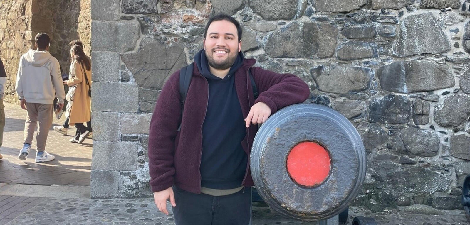 Student Miguel stands beside cannon at Carrickfergus Castle