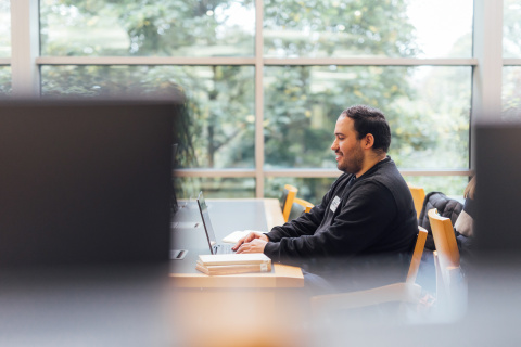 Male student working at laptop in McClay Library
