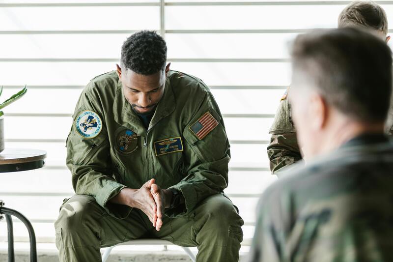 Military man sitting on chair looking down at floor