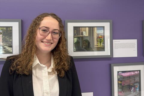 Student Morgan stands in front of their photo submission at the AEL photography competition