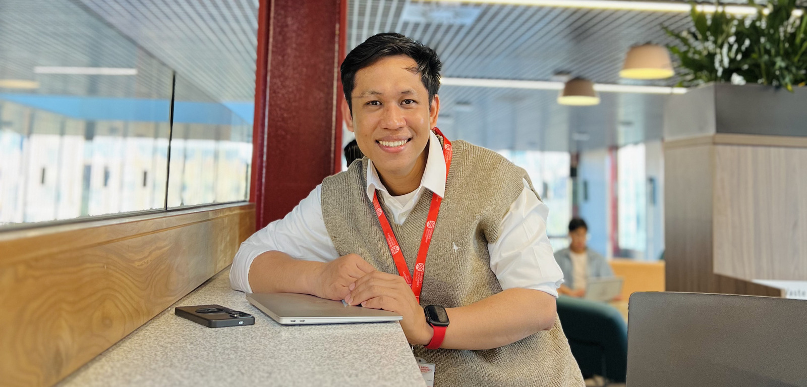 PhD student Muhammad poses for photo with Queen's red lanyard on