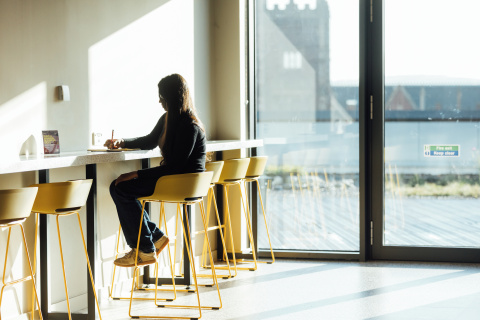 Female student writing at table in One Elmwood