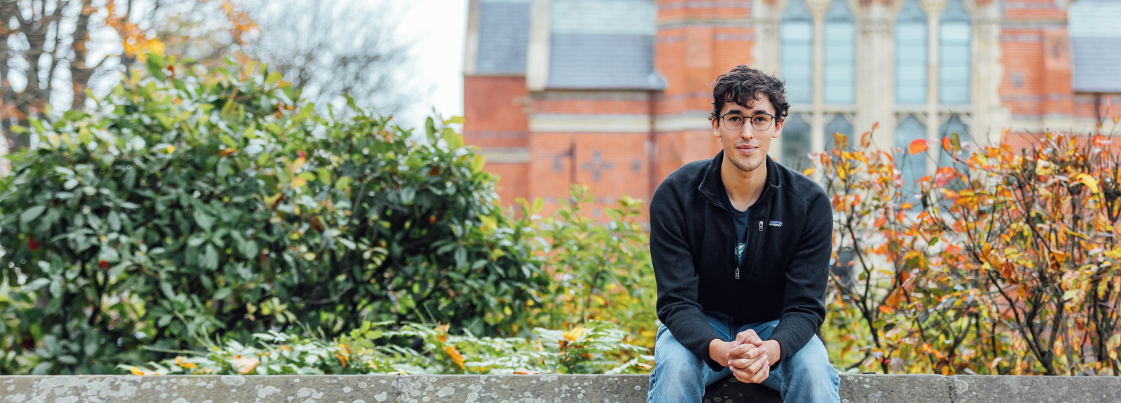 North American student sitting on the wall in front of the Lanyon