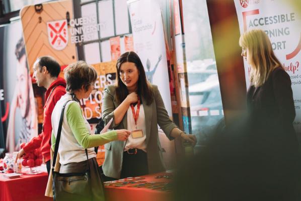 Staff member talks to visitor at offer holder event stall