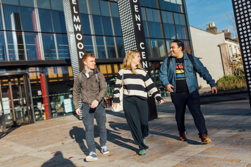 Three students walking out of One Elmwood building