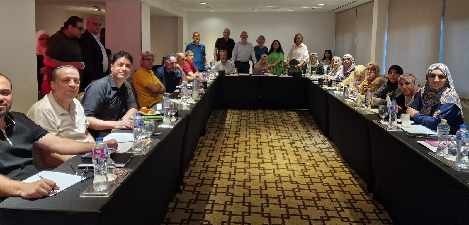 A large group of academics are seated in a conference room looking towards the camera
