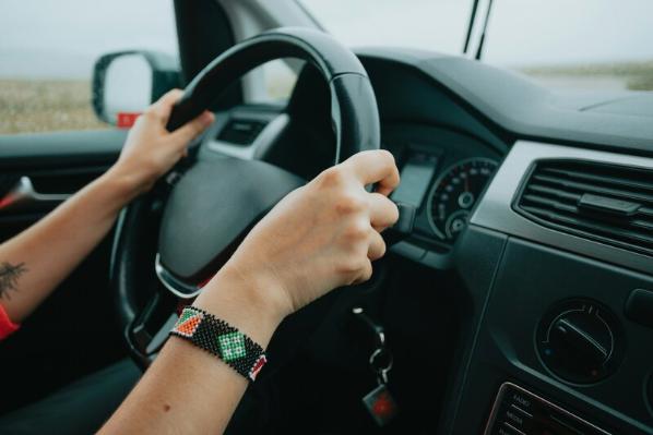 Person driving car with hands on steering wheel