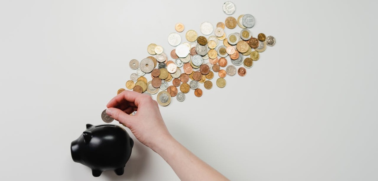 Coins going into black piggy bank