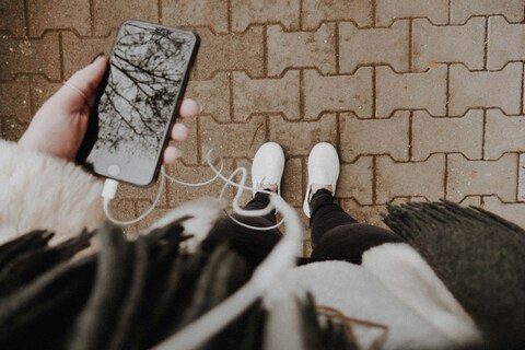 Person listening to podcast through earphones on their phone