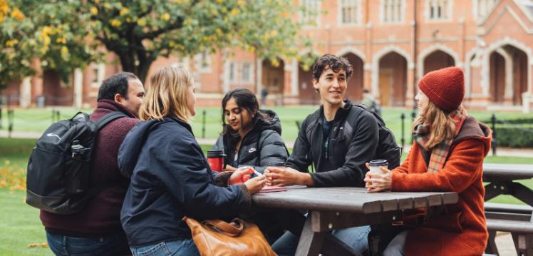 QUB student sit together on bench in the quad