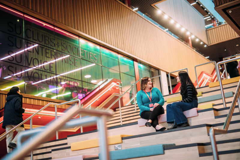 Staff member and student sitting on One Elmwood steps