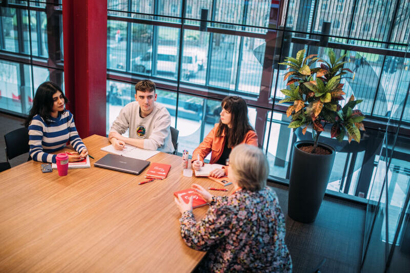 Students and staff sitting around table in One Elmwood