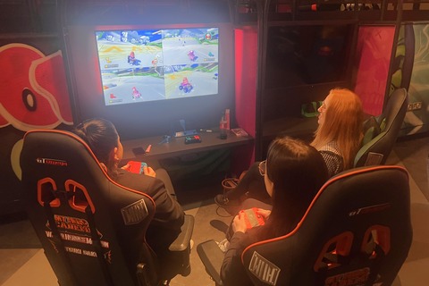 Three females playing Mario Kart in Reboot cafe