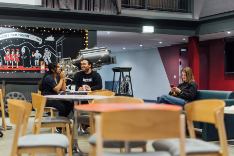 Male and female student sitting together in QFT foyer