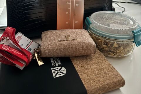 Queen's notebook, student card and purse on top of table