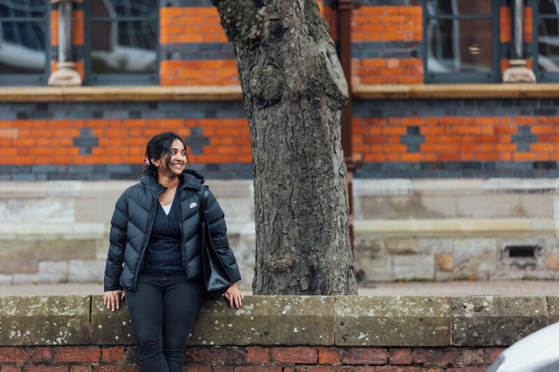 Student Sanjana sits on wall smiling