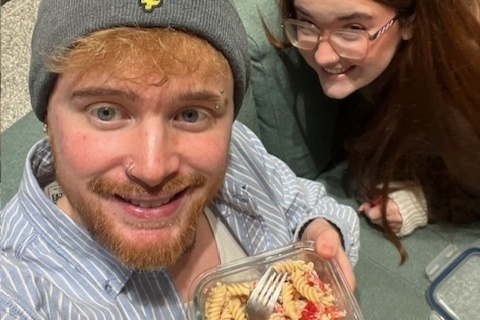 Marketing student Scott holding bowl of pasta and sitting beside female student