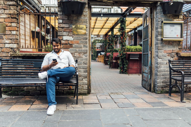 Male student sits on bench outside the Dirty Onion