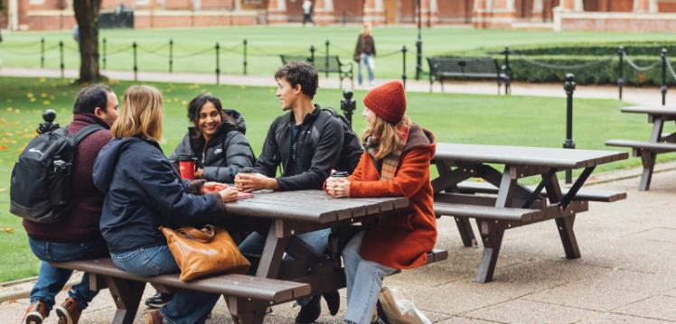 Group of students sitting together on bench in the Quad