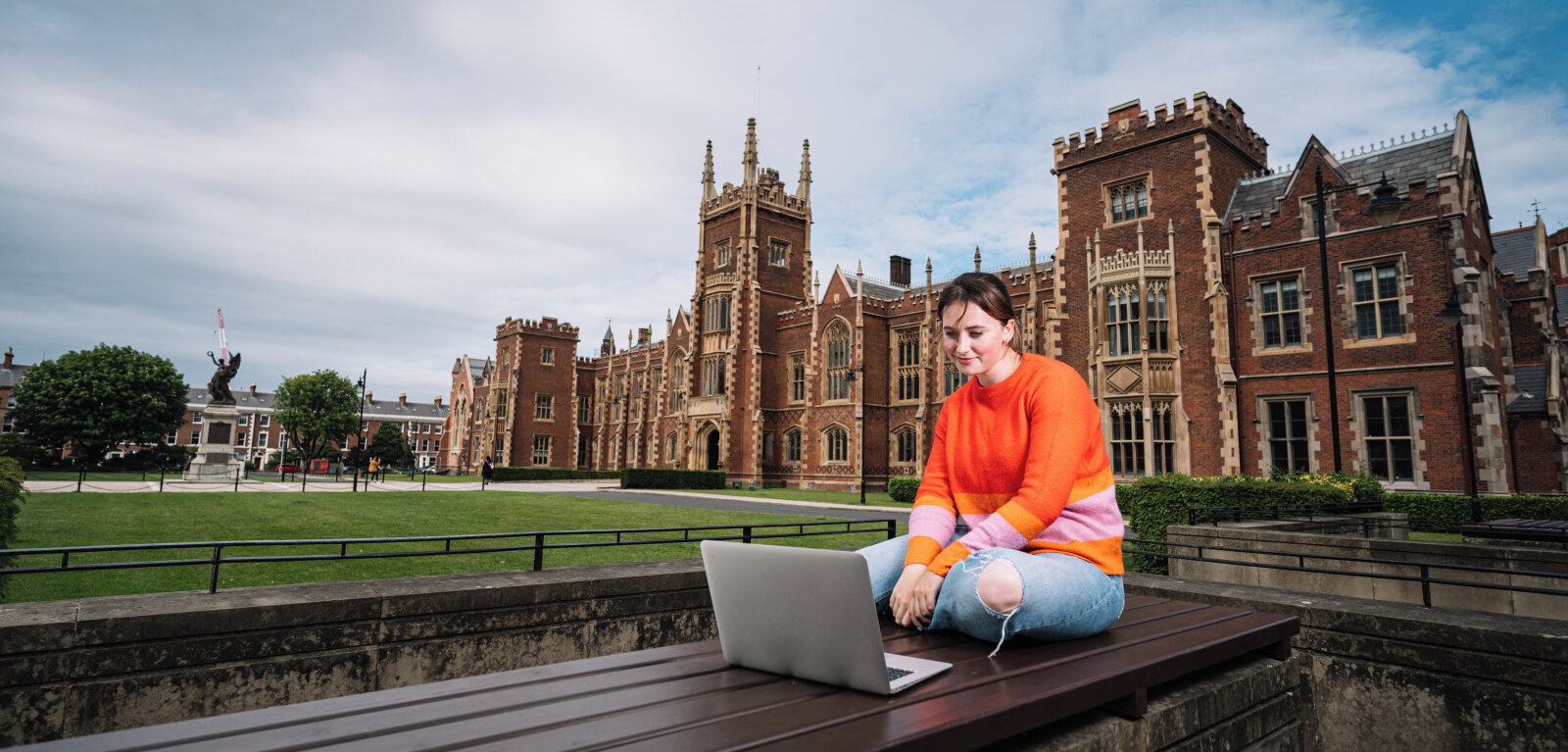 Student working on laptop in front of Lanyon