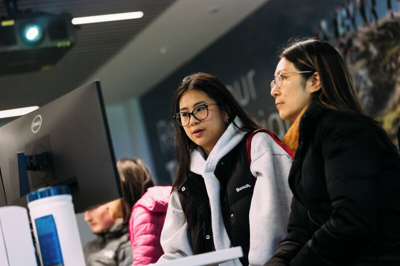 Student and parent stand in front of computer monitor