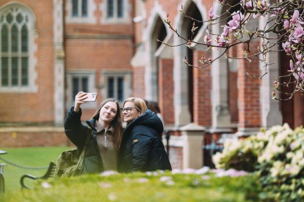 Female student and her parent/guardian taking selfie together in Queen's Quad