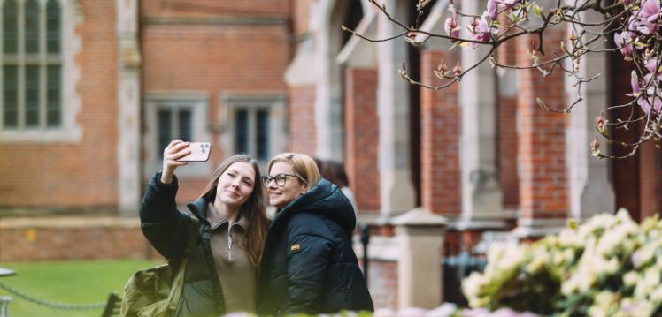 Female student and their parent taking a selfie on the quad
