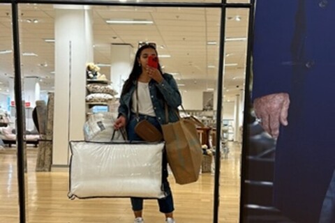 Student posing in front of mirror holding a pillow