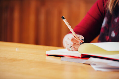 Student writing in red notebook