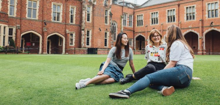 Three students sitting on the lawn in the quad