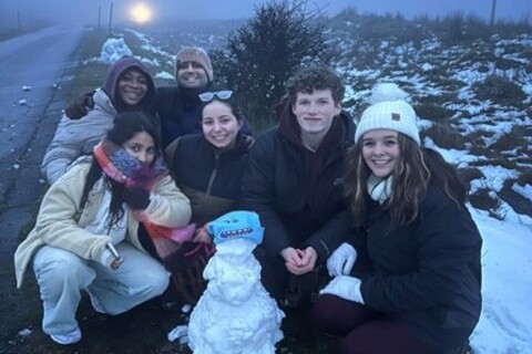 Group of students huddled around a snowman