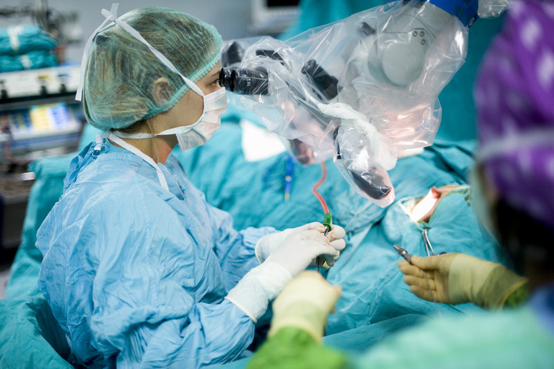 A female surgeon using a surgical microscope during surgery
