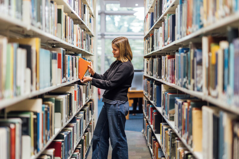 Student Tessa looking at books in McClay Library