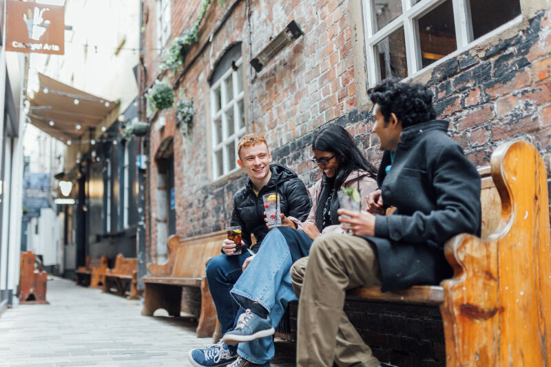 Three students sitting together on bench in Joy's Entry