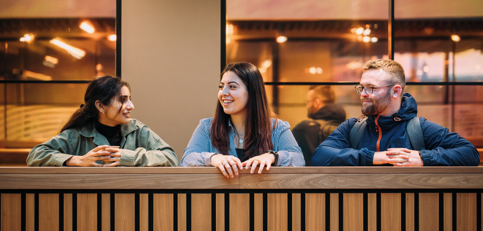 Three students stand together at balcony in One Elmwood