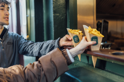 Two students reaching for chip cones from the Poke Club in Belfast