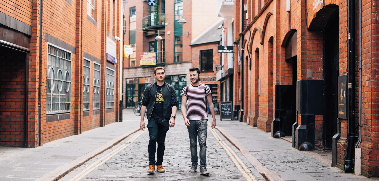 Two male students walking down cobblestoned street in Cathedral Quarter