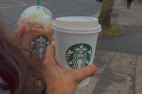 Two students holding drinks from Starbucks