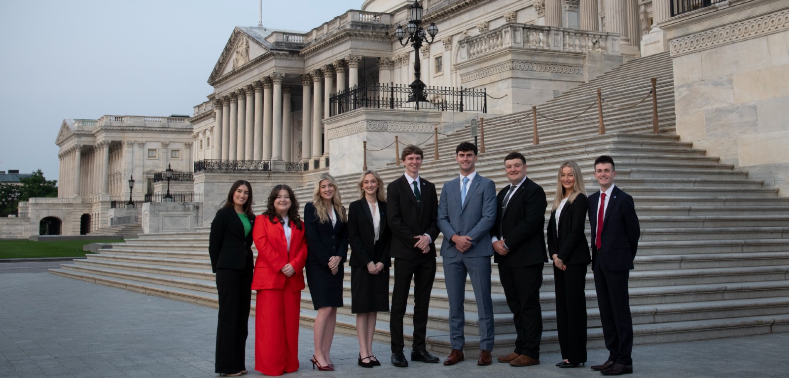 A group of Queen's students on Capitol Hill, Washington DC, stand looking at the camera and smiling