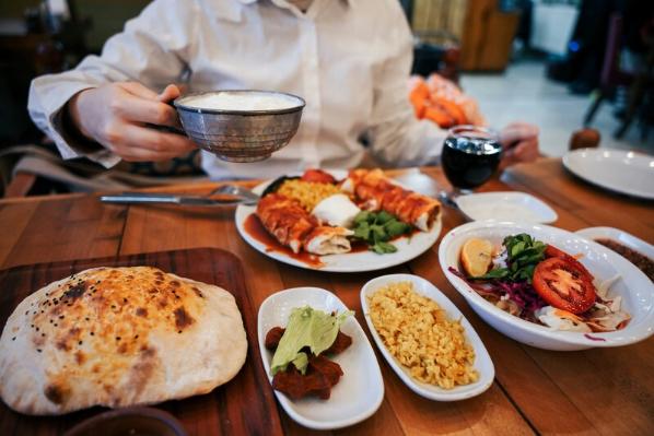 Woman eating from various plates of food on table
