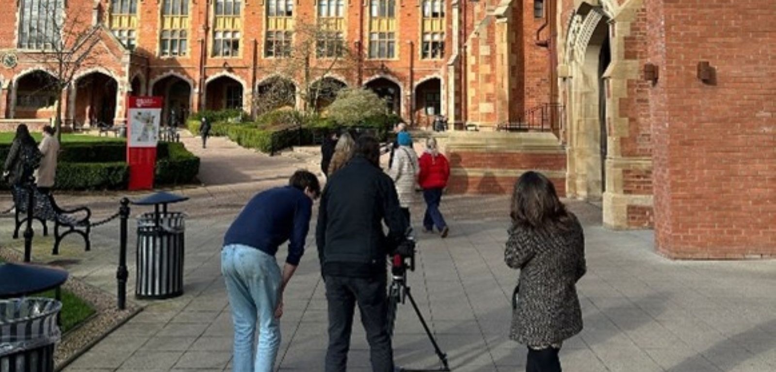 People using a film camera on the campus of Queen's