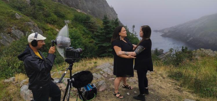 Man recording two women singers overlooking mountains and the sea