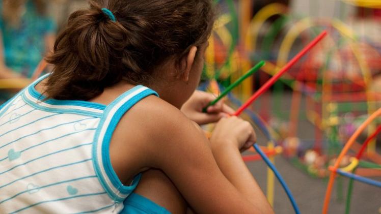 child playing with multicoloured wire puzzle