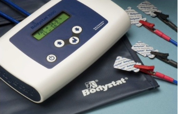 A picture of the Bodystat machine on a blue table with the sticky pads ready to be applied to a patient.