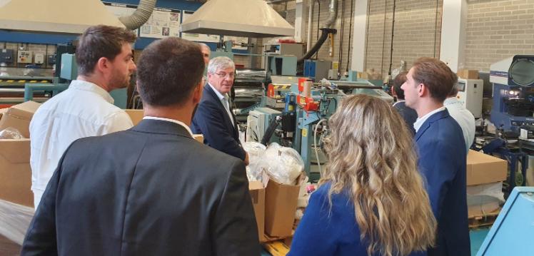 A group of people standing in front of an extruder machine in the PPRC laboratory