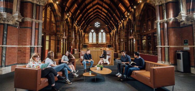 A group of students sitting on brown leather sofas doing group work