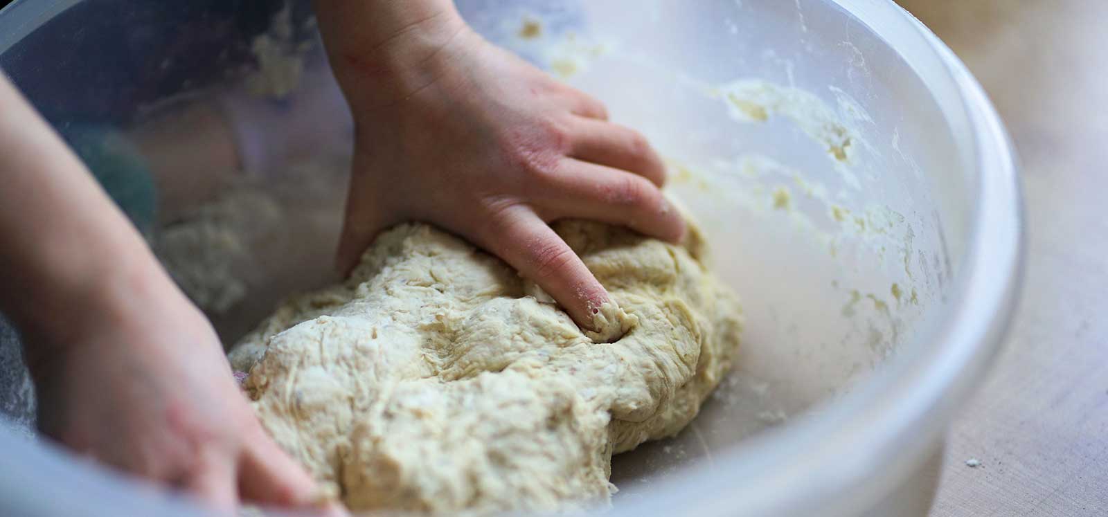 close up of a bowl, hand and dough