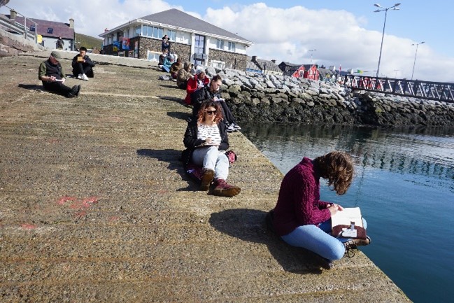 People sitting down and writing by the water